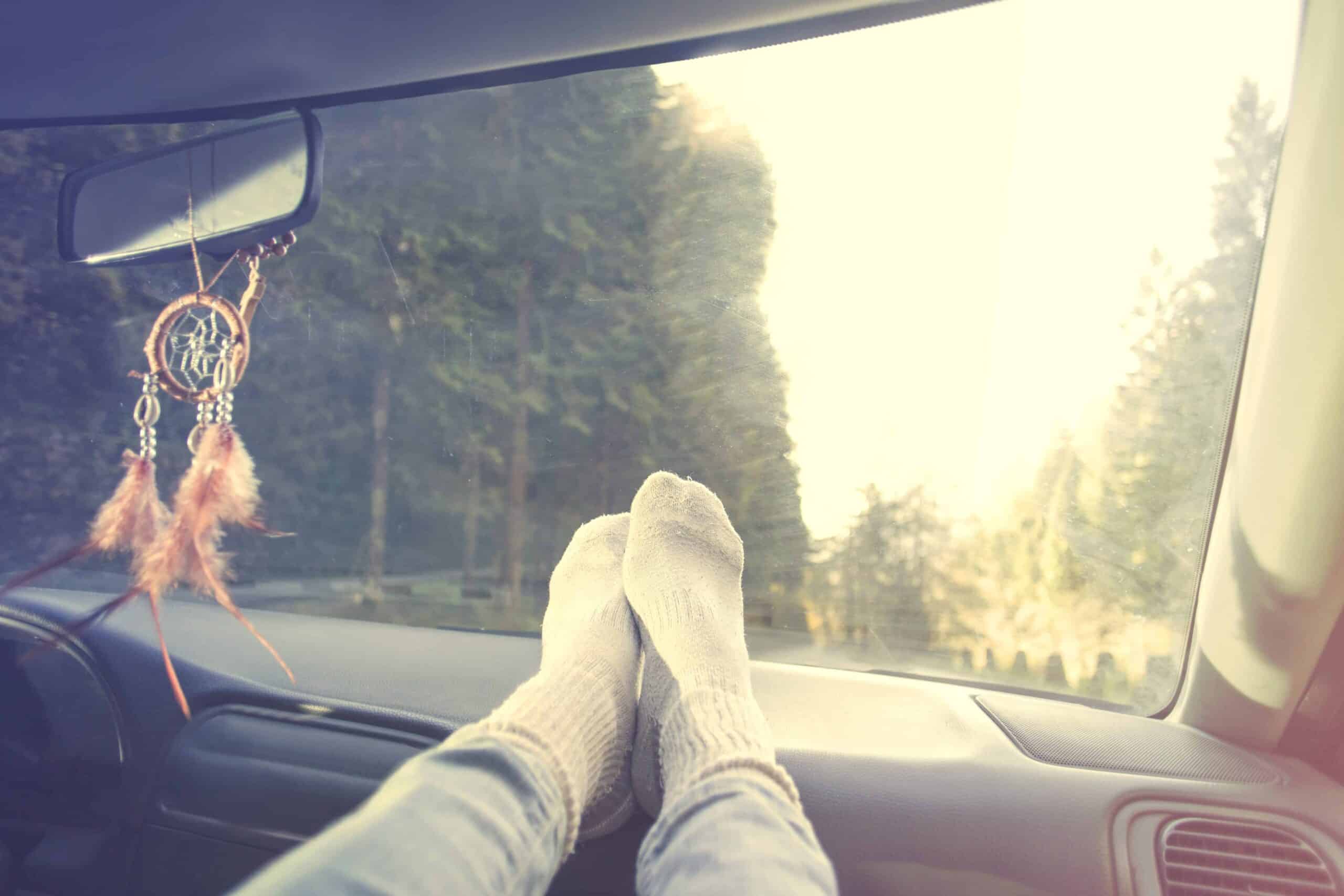 Relaxed person with feet on dashboard during car trip