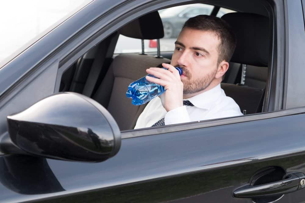homem bebendo água no carro